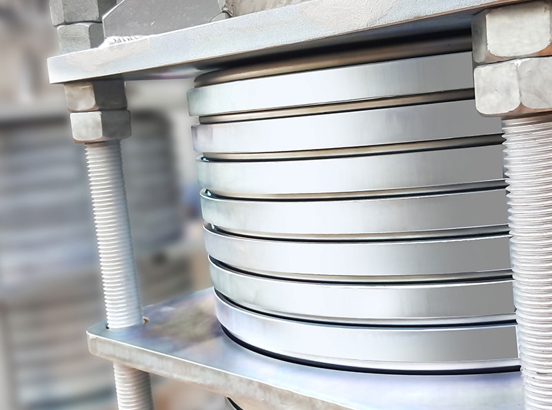 Expansion bellows can be designed with reinforcing or equalizing rings which are located around the outside of the convolutions, preventing bellows being forced out from high pressure. The principal purpose of these devices is to reinforce the bellows under internal high pressure, so that bellows does not squirm and equalize movement among all the convolutions.Equalizing and reinforcing rings are made of carbon steel, stainless steel or other suitable alloys.Reinforcing rings are usually Tee shaped in cross section and equalizing rings are normally fabricated from tubing or solid round bars of suitable material.Bellows with reinforcing or equalizing rings can be made for any type of expansion joint (axial, lateral or angular etc.). The disadvantage of these bellows is the increased stiffness and limited movement of the bellows.