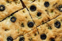 Freshly baked foccacia bread topped with herbs and olives