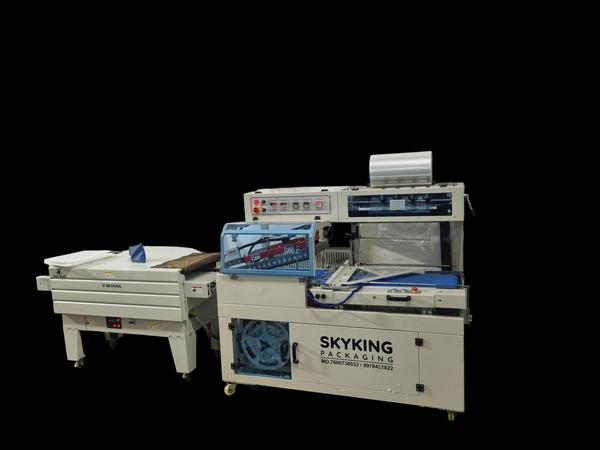 Sky King Fully Automatic L-Sealer with Shrink TunnelSky King Packaging proudly presents the Fully Automatic L-Sealer with Shrink Tunnel, an advanced packaging solution engineered to meet the diverse needs of industries such as stationery, consumer goods, and kitchenware. This machine is ideal for applications including notebook shrink wrapping, small box packaging, chopping board packing, and more.Key Features:Automated Operation: Streamlines the packaging process with minimal manual intervention, enhancing productivity and reducing labor costs.Versatile Application: Accommodates a wide range of products, including notebooks, small boxes, chopping boards, and similar items, offering flexibility across various packaging needs.High-Quality Sealing: Delivers strong and precise seals, improving the protection and presentation of packaged products.Integrated Shrink Tunnel: Features a built-in shrink tunnel that uniformly applies heat to shrink film, resulting in a tight and professional finish.User-Friendly Interface: Equipped with an intuitive control panel for easy operation and quick adjustments, minimizing downtime.Technical Specifications:Power Supply: Designed to operate efficiently with standard industrial power sources, ensuring compatibility and energy efficiency.Sealing Dimensions: Customizable sealing dimensions to accommodate various product sizes, providing adaptability to specific packaging requirements.Packaging Speed: Capable of handling multiple packages per minute, adjustable to match production demands and optimize workflow.Film Compatibility: Compatible with various shrink films such as POF, PVC, and PE, offering flexibility in material selection.Machine Dimensions: Compact and robust design to fit seamlessly into existing production lines without occupying excessive space.Applications:Notebook Shrink Wrapping: Provides secure and aesthetically pleasing packaging for notebooks, protecting them from dust and damage.Small Box Packaging: Ideal for wrapping small boxes, ensuring tamper-evident seals and enhanced product presentation.Chopping Board Packing: Effectively packages chopping boards, maintaining hygiene and preventing scratches during transit.General Merchandise: Suitable for a variety of other products requiring shrink-wrapping, demonstrating versatility across industries.Why Choose Sky King Packaging?Expertise: As a leading manufacturer based in Rajkot, Gujarat, Sky King Packaging specializes in designing and producing high-quality packaging machinery tailored to diverse industry needs.Customization: We understand that each client has unique requirements. Our machines are designed to be flexible, accommodating various specifications to ensure optimal performance.Quality Assurance: Committed to excellence, we utilize premium materials and adhere to stringent quality control measures, ensuring our machines deliver reliable and consistent results.Global Reach: Serving clients across India and exporting internationally, Sky King Packaging has established a reputation for delivering innovative and efficient packaging solutions worldwide.For more information, customization options, and pricing details, please contact Sky King Packaging. We are dedicated to providing solutions that enhance your operational efficiency and product quality.
