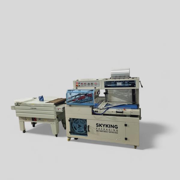 Sky King Fully Automatic L-Sealer with Shrink TunnelSky King Packaging proudly presents the Fully Automatic L-Sealer with Shrink Tunnel, an advanced packaging solution engineered to meet the diverse needs of industries such as stationery, consumer goods, and kitchenware. This machine is ideal for applications including notebook shrink wrapping, small box packaging, chopping board packing, and more.Key Features:Automated Operation: Streamlines the packaging process with minimal manual intervention, enhancing productivity and reducing labor costs.Versatile Application: Accommodates a wide range of products, including notebooks, small boxes, chopping boards, and similar items, offering flexibility across various packaging needs.High-Quality Sealing: Delivers strong and precise seals, improving the protection and presentation of packaged products.Integrated Shrink Tunnel: Features a built-in shrink tunnel that uniformly applies heat to shrink film, resulting in a tight and professional finish.User-Friendly Interface: Equipped with an intuitive control panel for easy operation and quick adjustments, minimizing downtime.Technical Specifications:Power Supply: Designed to operate efficiently with standard industrial power sources, ensuring compatibility and energy efficiency.Sealing Dimensions: Customizable sealing dimensions to accommodate various product sizes, providing adaptability to specific packaging requirements.Packaging Speed: Capable of handling multiple packages per minute, adjustable to match production demands and optimize workflow.Film Compatibility: Compatible with various shrink films such as POF, PVC, and PE, offering flexibility in material selection.Machine Dimensions: Compact and robust design to fit seamlessly into existing production lines without occupying excessive space.Applications:Notebook Shrink Wrapping: Provides secure and aesthetically pleasing packaging for notebooks, protecting them from dust and damage.Small Box Packaging: Ideal for wrapping small boxes, ensuring tamper-evident seals and enhanced product presentation.Chopping Board Packing: Effectively packages chopping boards, maintaining hygiene and preventing scratches during transit.General Merchandise: Suitable for a variety of other products requiring shrink-wrapping, demonstrating versatility across industries.Why Choose Sky King Packaging?Expertise: As a leading manufacturer based in Rajkot, Gujarat, Sky King Packaging specializes in designing and producing high-quality packaging machinery tailored to diverse industry needs.Customization: We understand that each client has unique requirements. Our machines are designed to be flexible, accommodating various specifications to ensure optimal performance.Quality Assurance: Committed to excellence, we utilize premium materials and adhere to stringent quality control measures, ensuring our machines deliver reliable and consistent results.Global Reach: Serving clients across India and exporting internationally, Sky King Packaging has established a reputation for delivering innovative and efficient packaging solutions worldwide.For more information, customization options, and pricing details, please contact Sky King Packaging. We are dedicated to providing solutions that enhance your operational efficiency and product quality.