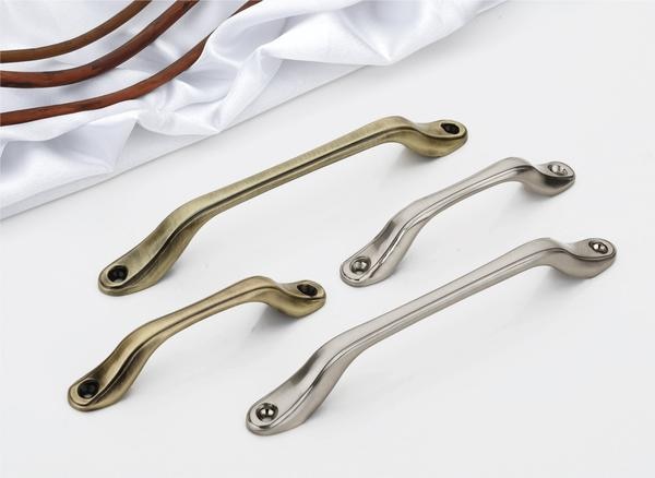 The design narrative of these handles centers around a harmonious balance of form and texture. The gently curved central bar introduces a tactile and visual softness, while the subtly flared bases provide a stable and contemporary anchor. The visible screw detail adds a touch of utilitarian charm, preventing the overall aesthetic from appearing overly polished. This deliberate fusion of smooth curves and defined edges ensures that these handles seamlessly integrate with a wide array of window designs, including mailey windows, and interior design vocabularies, from farmhouse chic to modern industrial settings.Forged from high-caliber, corrosion-resistant alloys, these handles are engineered to endure the demands of everyday interaction and exposure to the elements when used on windows, without succumbing to wear or environmental degradation, ensuring their refined appearance persists over time. The brushed nickel/silver renditions offer a contemporary and understated elegance, while the aged bronze introduces a sense of rustic sophistication, and the antique brass imparts a touch of vintage warmth. These premium handles offer a sleek design suitable for various window applications.