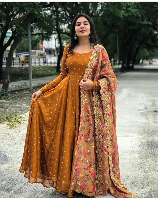 PALSANA Present Unveil timeless elegance with our Mustard Embroidered Gown, a masterpiece that seamlessly blends traditional craftsmanship with contemporary design.Crafted from luxurious georgette fabric, this gown features intricate zari thread and sequin embroidery, adding a touch of opulence to your ensemble. The rich mustard hue exudes warmth and sophistication, making it a perfect choice for weddings, festive occasions, or any special celebration.The accompanying printed dupatta adds a layer of grace, featuring delicate patterns that complement the gown's intricate embroidery. Its lightweight and airy fabric ensure comfort without compromising on style.Key Features:Fabric: Premium Georgette for a fluid and flattering silhouette.Embroidery: Detailed zari and sequin work on the front and back.Dupatta: Printed design with matching borders, crafted from soft net fabric.Fit: Fitted at the bust and waist, flaring gracefully towards the hem.Occasions: Ideal for weddings, receptions, festive gatherings, and formal events.Pair this ensemble with traditional jewelry and heels to complete your look. Embrace the fusion of tradition and modernity with this exquisite gown that promises to make you the center of attention.Located :International Fashion Market , Near Sitanagar Chowk , Punagam Road Surat