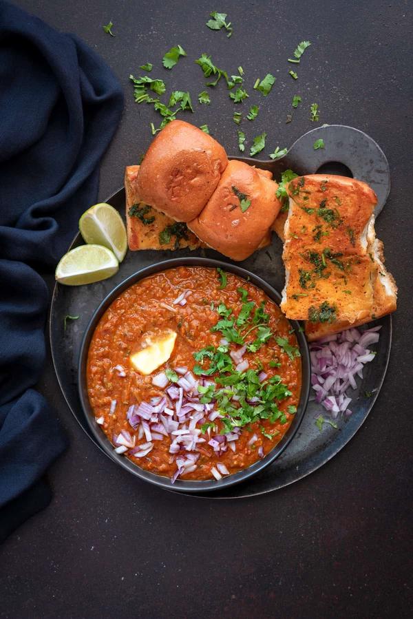 Experience the bold and unforgettable taste of Mumbai’s bustling streets with our authentic Pav Bhaji – a rich, buttery vegetable curry served with soft, golden-toasted bread rolls.

Crafted from a mouthwatering blend of mashed potatoes, peas, tomatoes, capsicum, and onions, the bhaji (vegetable gravy) is slow-cooked with a special house-made Pav Bhaji masala, bringing out deep, smoky, and spicy flavors. Finished with a generous dollop of butter and a squeeze of fresh lemon, every bite bursts with warmth and comfort.