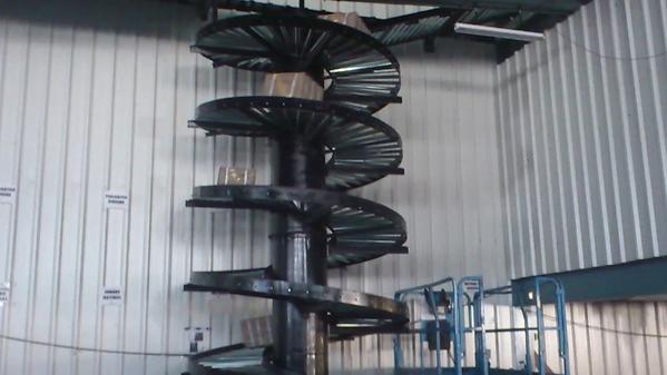 A spiral gravity conveyor is a material-handling / conveying equipment that uses gravity—not motors or electricity—to move items downward in a spiral path. Think of it as a vertical slide for boxes, packages, or crates, designed to transport goods between different levels of a facility efficiently and smoothly.Here’s how it works:It consists of a spiral-shaped track fitted with rollers.Items placed at the top move downward due to gravity, guided by the spiral structure.Since it doesn’t require power, it’s energy-efficient and low-maintenance.These conveyors are especially useful in warehouses, distribution centers, and manufacturing plants where space is tight and vertical movement is needed. They’re ideal for transferring cartons or crates from upper floors to ground level without damaging the contents.If you need to know if it’s right for your setup or what kinds of products it handles best? Advance Equipment Co. offers free consultation with that too.