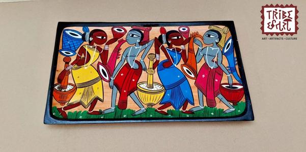 Wooden Hand Painted tray/PlatterThese hand-painted trays feature the vibrant and earthy Santhal painting style, a traditional tribal art form from the Santhal community of West Bengal.🎨 Art Style:Santhal paintings are known for their bold lines, rhythmic patterns, and vibrant storytelling.Common themes include tribal dances, music, nature, daily village life, and scenes of community bonding.The art reflects the joyous spirit and close connection to nature of the Santhal people.🖌️ Craftsmanship:Each tray is individually hand-painted by rural artisans. The figures are often depicted in motion dancing, playing instruments, or farming — giving the artwork a dynamic and lively character.🌿 Cultural Value:These trays celebrate tribal heritage and indigenous identity, making them not just decorative items but also narratives of a living culture.Perfect for ethnic décor, gifting, or cultural collections.Available at Tribe Chatari, these trays a one-of-a-kind pieces that carry the spirit of rural India.size --9x15