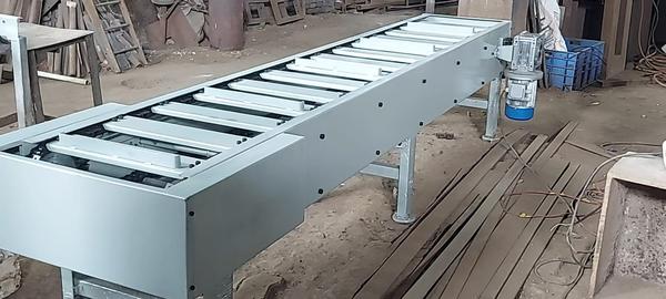 A slat conveyor is a type of industrial conveyor system designed to move heavy or oddly shaped items across a production line using a series of flat slats attached to a chain.🛠️ Key Features•	Slats: Made from metal, wood, or plastic, these flat panels are mounted on chains to form a continuous moving surface.•	Chain Drive: The slats are driven by a motorized chain system, ensuring consistent movement.•	Customizable: Width, length, and slat spacing can be tailored to specific applications.🏭 Common Uses•	Assembly Lines: Ideal for automotive, machinery, and appliance manufacturing.•	Packaging Units: Used to transport boxes, bottles, and cartons.•	High-Temperature Environments: Suitable for moving hot or heavy items that belts can't handle.✅ Advantages•	Stable surface for transporting items•	Can support fixtures for robotic or manual assembly•	Works well in harsh or high-load conditions•	Allows for precise positioning and indexing🚫 Limitations•	Not suitable for curved paths•	Doesn’t allow product accumulation (items can't bunch up)•	Less flexible than roller or overhead conveyors for changing product typesIf you're curious about how these systems are used in specific industries or want help designing one, please send your enquiry on advanceequipments@hotmail.com 