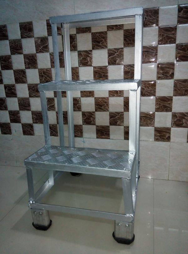 aluminum step stool is a compact, lightweight, and portable platform designed to provide a small elevation boost for tasks that require reaching slightly higher areas. It's commonly used in homes, offices, warehouses, and industrial settings for safe and convenient access to elevated items or workspaces. Key Features:Material:Made from lightweight, corrosion-resistant aluminum.Durable and rust-free, ideal for both indoor and light outdoor use.Design:Compact frame with 1 to 3 steps, depending on height.Often foldable for easy storage and transport.Some models include a top handle or safety rail for additional support.Step Surface:Anti-slip tread or textured surface on steps to prevent slipping.Wide steps for added comfort and stability.Feet/Base:Equipped with non-slip rubber feet to ensure grip and prevent movement.Some industrial models include wide flared bases for extra stability.Weight Capacity:Typically supports between 225–300 lbs, depending on model and grade.Available in ANSI Type II (225 lbs), Type I (250 lbs), or Type IA (300 lbs) ratings.Mobility Options (optional):Some designs include wheels or casters with locking mechanisms for easy repositioning. Common Applications:Household tasks (e.g., changing light bulbs, reaching kitchen cabinets)Retail and office use (stocking shelves, accessing files)Maintenance and repairLight industrial or warehouse useSIZE - 3 STEP