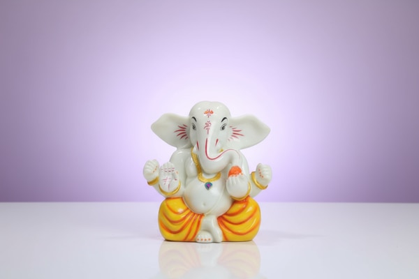 Bring home a symbol of calmness and auspicious beginnings with this Marble Lord Ganesha Murti (8 Inch). Designed with a smooth white finish, neat gold and red detailing, and a vibrant orange dhoti, this idol represents peace, wisdom, and positive energy. Lord Ganesha is shown in a seated posture holding a laddoo, symbolizing joy, success, and fulfillment.The washable marble material makes maintenance easy, ensuring long-lasting beauty for daily worship or spiritual decor. Its stable base and compact size allow perfect placement in home temples, living rooms, office desks, or study corners.This statue is also a thoughtful choice for gifting during housewarming ceremonies, festive celebrations like Ganesh Chaturthi and Diwali, birthdays, anniversaries, family occasions, office openings, and business inaugurations.Product Details:Height: 8 inchesWidth: 6 inchesDepth: 3.5 inchesMaterial: Washable marbleIdeal for: Home temple, pooja, decor, spiritual giftingInvite positive energy and a peaceful presence into any space, or present this Ganesha murti as a heartfelt gift of blessings.