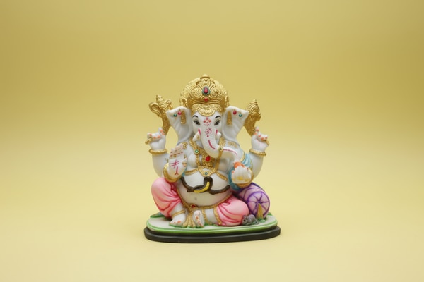 Bring home divine grace with this Golden Crown Ganesha Murti (7.5 Inch). The idol features a beautifully embossed golden mukut, pastel pink and aqua attire, and finely crafted features that add a calm and positive presence to your home.Made with washable marble material and a matte painted finish, this sculpture offers a soft, elegant look that blends easily with any décor style. The stable base allows placement in home temples, living rooms, offices, and festive arrangements.Lord Ganesha is shown holding symbolic shankhs for protection and power, while His blessing hand and laddoo represent happiness and prosperity.Sculpture Details:Height: 7.5 inchesWidth: 6.5 inchesDepth: 4 inchesMaterial: Washable marbleFinish: Matte painted finishIdeal for: Home temple, decor, spiritual giftingA meaningful choice for gifting on housewarmings, Ganesh Chaturthi, Diwali, birthdays, anniversaries, and business openings.