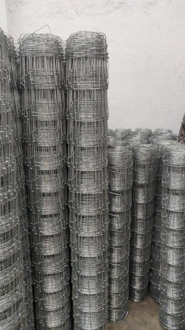 A wire mesh fence for cattle and sheep is a galvanized steel fence, often called a field fence or grassland fence, designed for containing livestock and protecting property. It features a graduated mesh with smaller openings at the bottom to prevent small animals from escaping or entering, while larger, sturdy horizontal and vertical wires create a strong barrier for larger animals. 