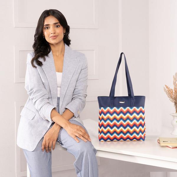Upgrade your everyday style with this elegant and functional women’s tote handbag, designed for modern lifestyles. Crafted with premium vegan leather and beautifully handcrafted fabric, this bag blends durability with eye-catching aesthetics. The vibrant patterned exterior paired with a sleek solid top adds a sophisticated yet trendy touch—perfect for work, shopping, or casual outings.Designed with practicality in mind, this handbag features a spacious main compartment that comfortably fits your daily essentials like notebooks, tablet, wallet, and more. Inside, you’ll find a secure internal zipper pocket to keep valuables safe and organized. The back zip pocket allows quick access to frequently used items like your phone or keys, while the additional external zipper pockets enhance storage convenience.The sturdy zipper closure ensures everything stays secure, while the water-resistant inner lining protects your belongings from accidental spills. With strong dual shoulder straps, this bag offers comfortable carrying throughout the day without compromising on style.Lightweight yet durable, this tote is ideal for women who need a reliable everyday bag with a fashionable edge. Whether you're heading to the office, college, or a casual day out, this handbag delivers the perfect balance of utility and elegance.